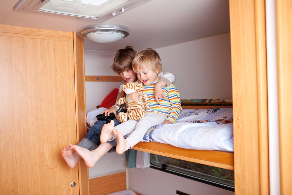 two kids playing on the top bunk of an RV