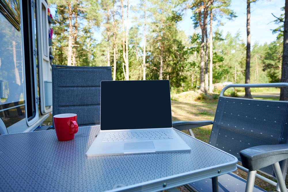 A laptop on a table outside an RV for an outdoor RV home office setup.