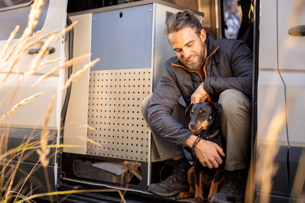 Man and dog in the entry of a van. Successful RV living with pets like this requires planning!