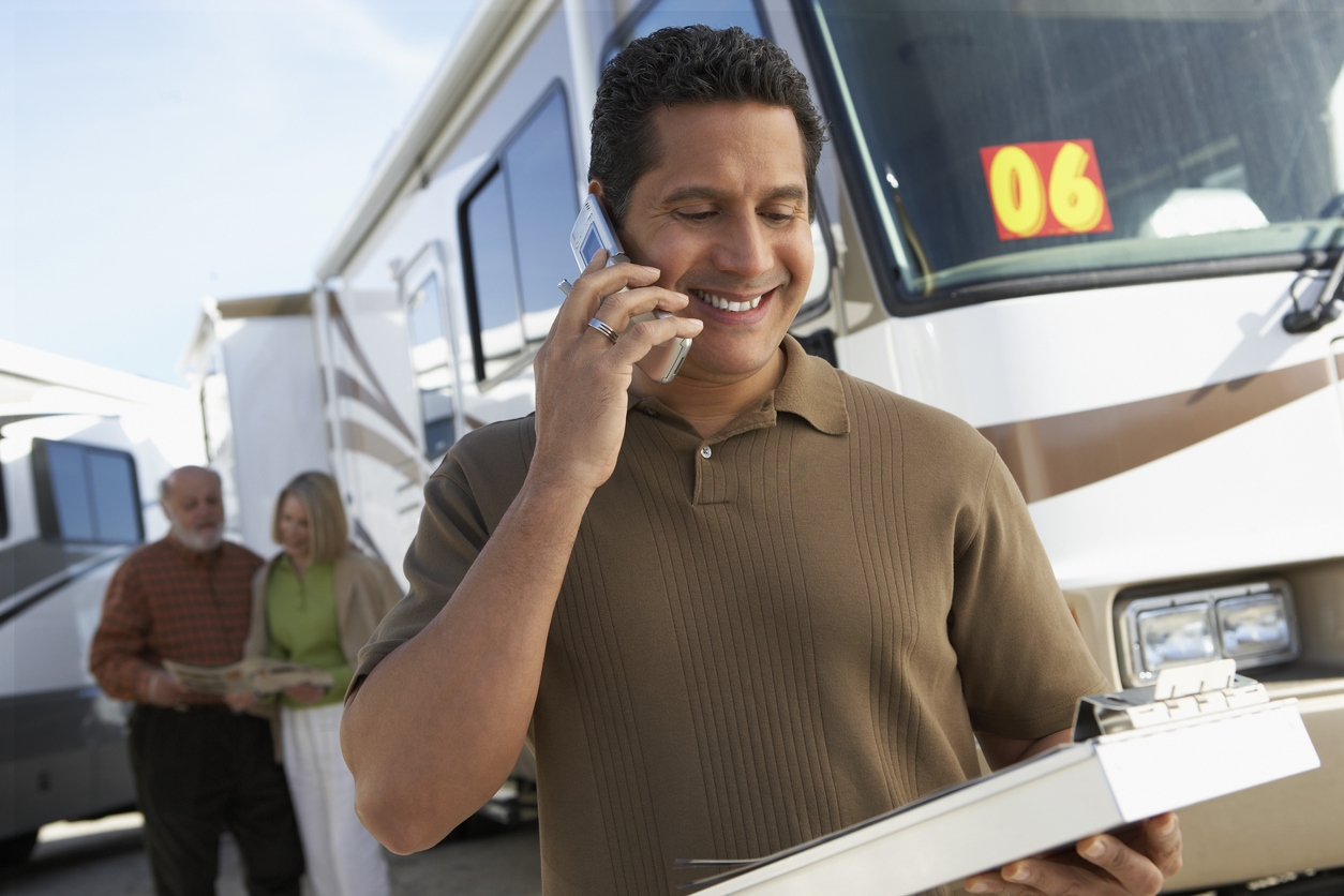A man on his cell phone in front of an RV. We answer the question: Should I sell my RV myself?