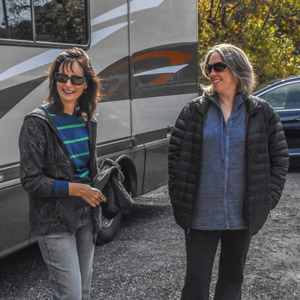 Two women outside of an RV. The question of "Should I sell my RV myself" comes down to time vs. money.