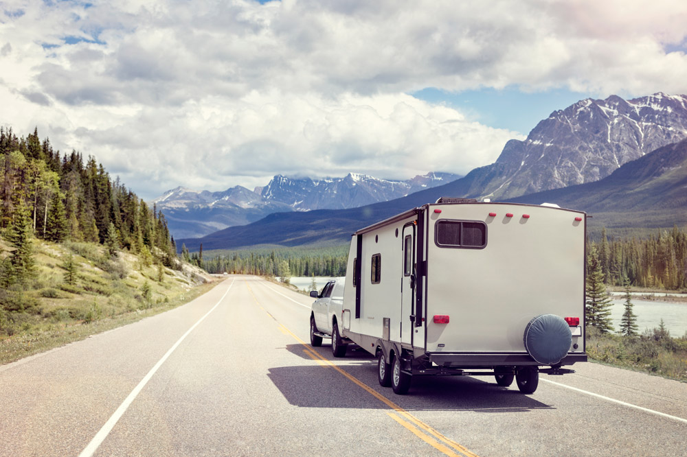 A truck tows a travel trailer through the mountains.