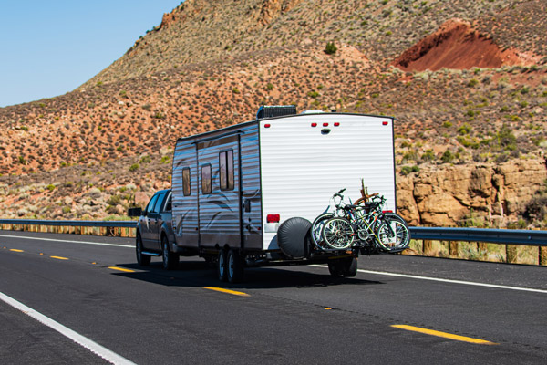 A truck tows a trailer down the road. Our tow guide shows you what your truck can tow.