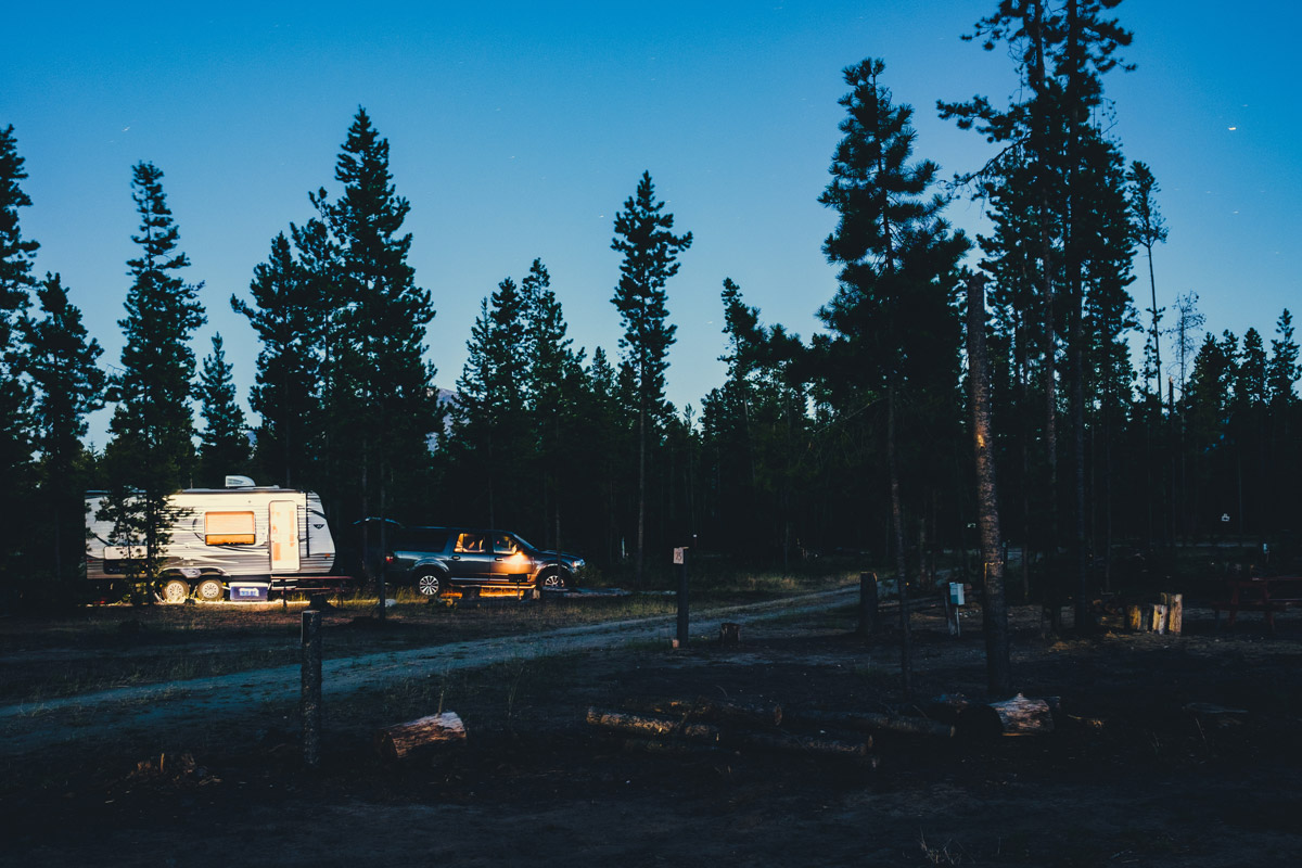 A travel trailer parked in the woods in a blog about Must-Make RV New Year's Resolutions