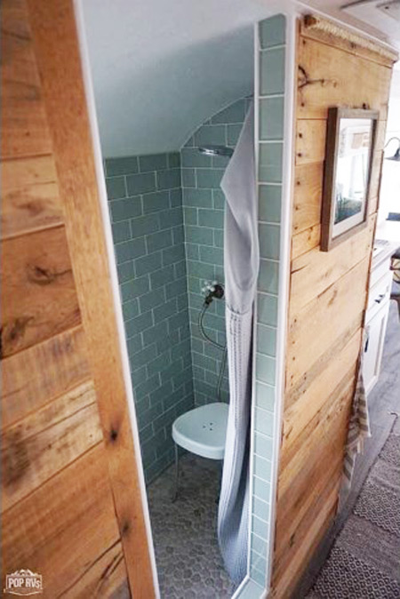 Green tiled bathroom and wooden walls in a skoolie for sale