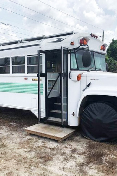 The white and teal exterior of a renovated school bus for sale