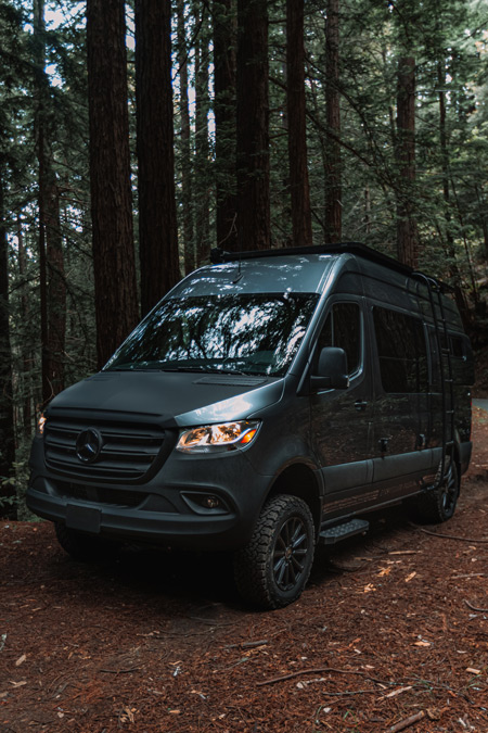 A Storyteller Overland Stealth MODE adventure van in the woods