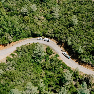 TAXA Mantis Overland RVs drive on a winding road through trees