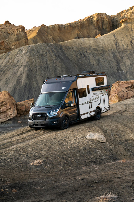 A Winnebago EKKO drives down a mountainous desert landscape. This is one of the overland RVs for sale on RVUSA