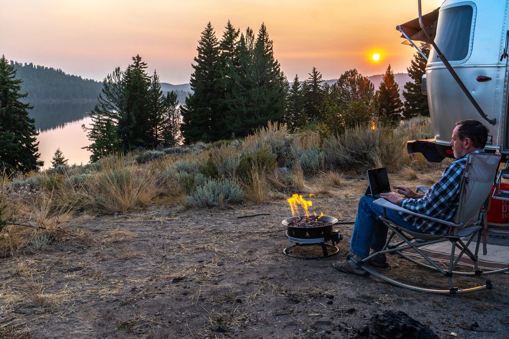 A man works on his computer at a campsite. Remote work continues to be popular in 2022.