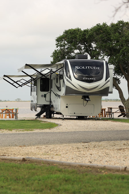 A Grand Design Solitude fifth wheel is parked on the waterfront at an RV park. This is one of the top 10 most viewed RVs on RVUSA