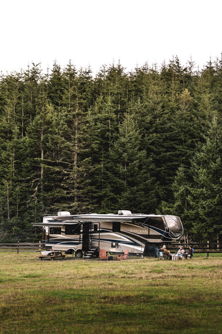 A Keystone Montana, one of the Top 10 most viewed RVs on RVUSA, Fifth wheel is parked in front of a dense forest of trees.