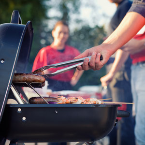 A man grills brats at an RV football tailgate