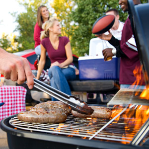 A man grills burgers and more RV tailgating recipes while his friends hang out in the background. 