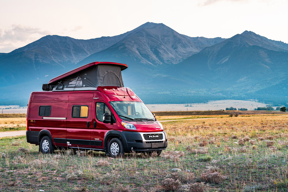 A Winnebago camper van with a pop top in front of a mountain range. This is one of the best 2023 RV models.