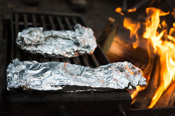 Foil pack recipes being roasted over the campfire on a grate. 